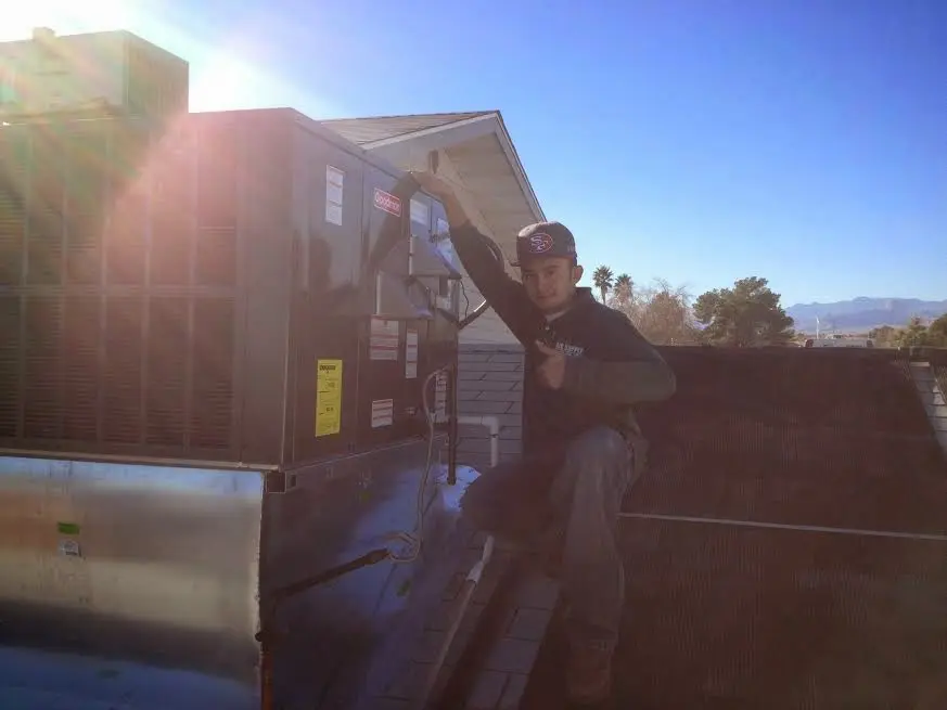 HVAC technician performing AC Tune-Up on a rooftop unit in Woodward
